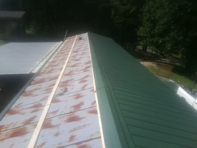 Old rusted panels beside newly installed green metal roofing — Wind Damage Roof Repair by Roofing Brothers in Sanford