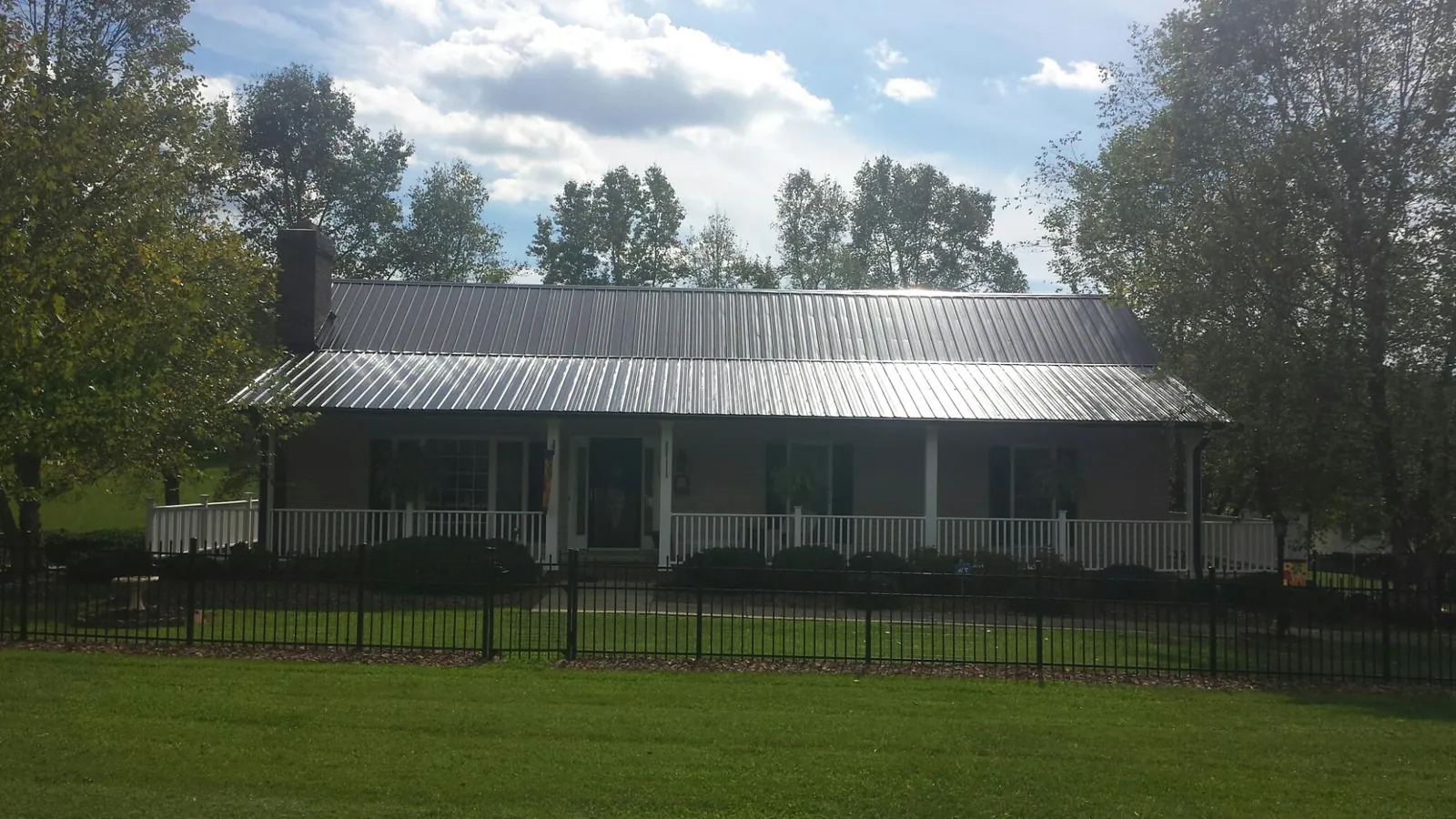 Gray metal roof on a brick ranch with a full width front porch — Gutter Guard Installation work by our crew in Sanford
